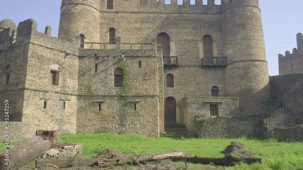 Camera tilt up from ground to reveal low angle view of Fasilides Castle southern facade and tower in Gondar, Ethiopia Camera tilt up from ground to reveal low angle view of Fasilides Castle southern facade and tower in Gondar, Ethiopia