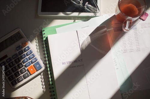 Retirement portfolio on sunny table with tea and calculator