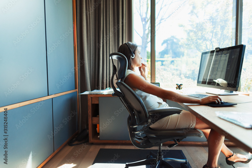Businesswoman working at desk in sunny office Businesswoman working at desk in sunny office