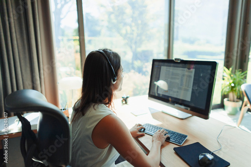 Businesswoman with headset working at computer in home office