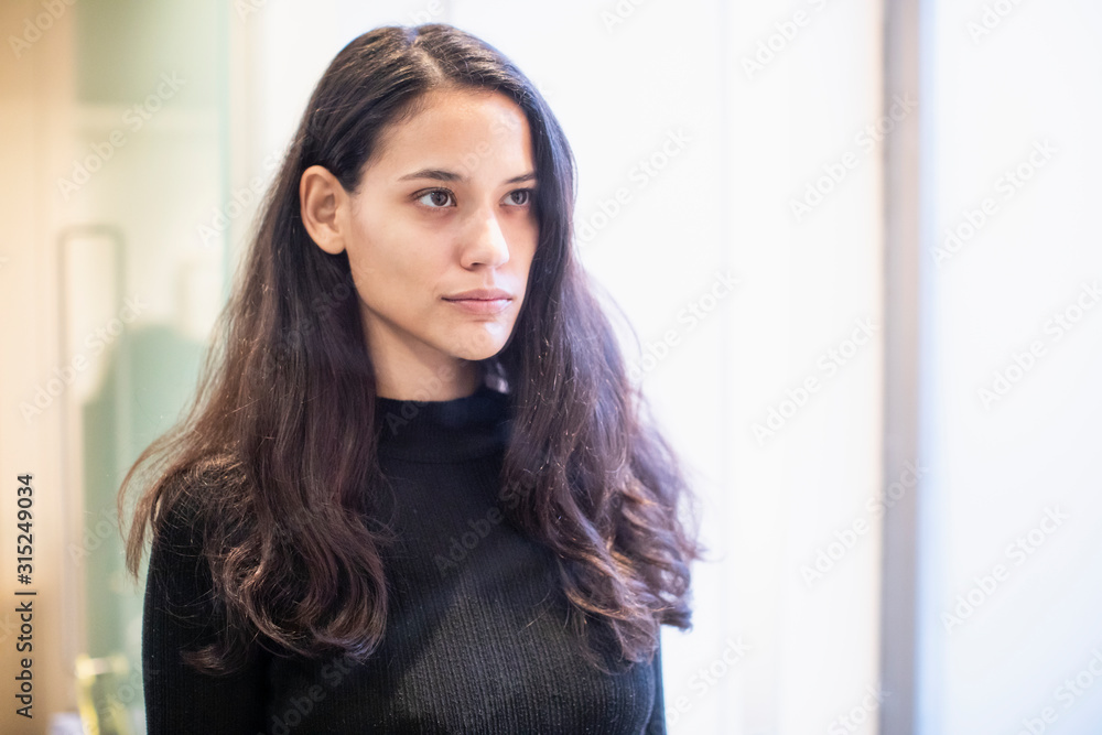 Serious brunette woman looking at reflection in bathroom mirror Serious brunette woman looking at reflection in bathroom mirror
