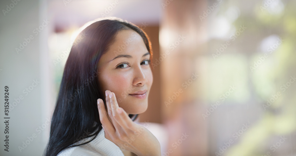 Portrait confident young woman applying moisturizer to face Portrait confident young woman applying moisturizer to face