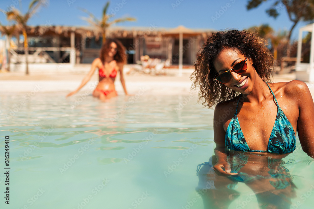 © Paul Bradbury/Caia Image - Portrait confident young woman in bikini swimming in sunny ocean