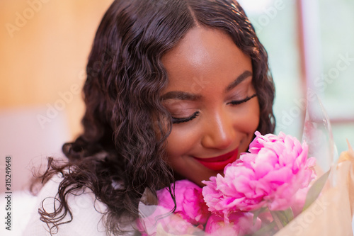 Close up serene young woman smelling fresh pink peony flowers photo