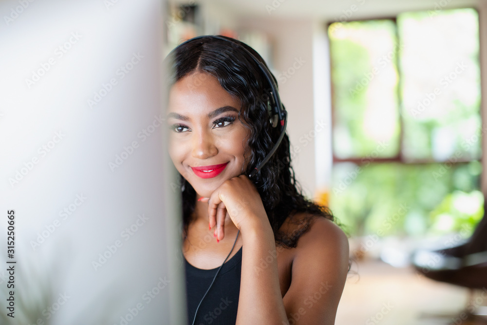 © Tom Merton/Caia Image - Young woman with headset working from home at computer