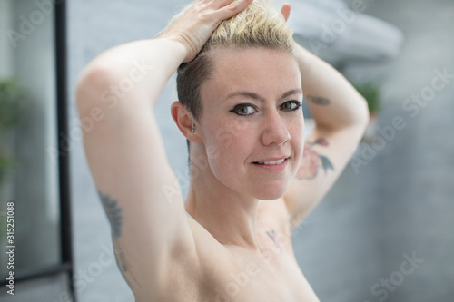 Portrait confident beautiful woman with tattoos in bathroom photo