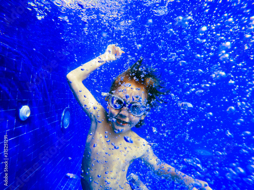 Portrait playful boy swimming underwater in blue swimming pool