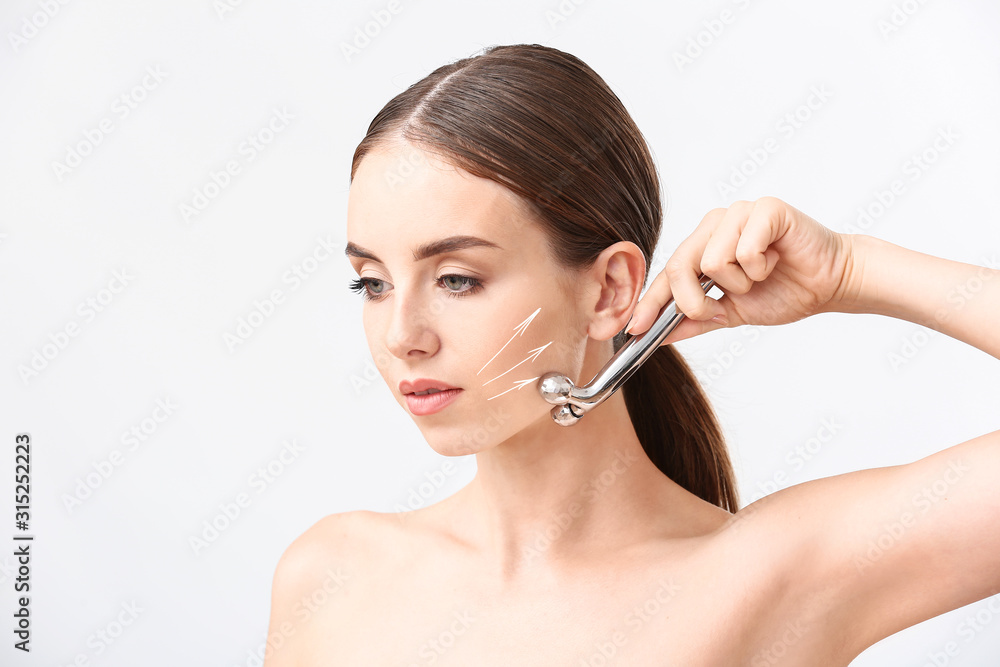 Fototapeta premium Beautiful woman massaging her face against white background