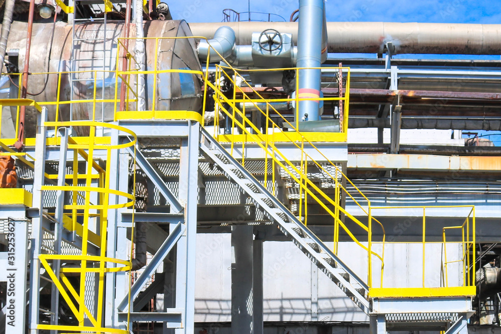 Large iron tanks, ladders and protective fencing pipes equipment and machine tools valves heat exchangers at a petroleum refining petrochemical chemical industrial plant