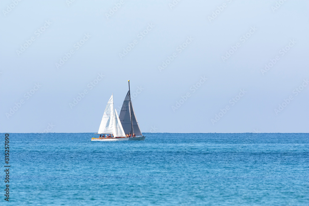 two sailboats are sailing out to sea