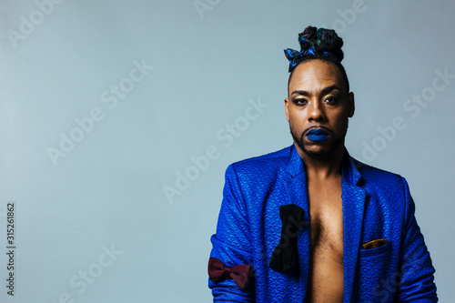 Studio portrait of a man with blue outfit and blue lips. Meditative