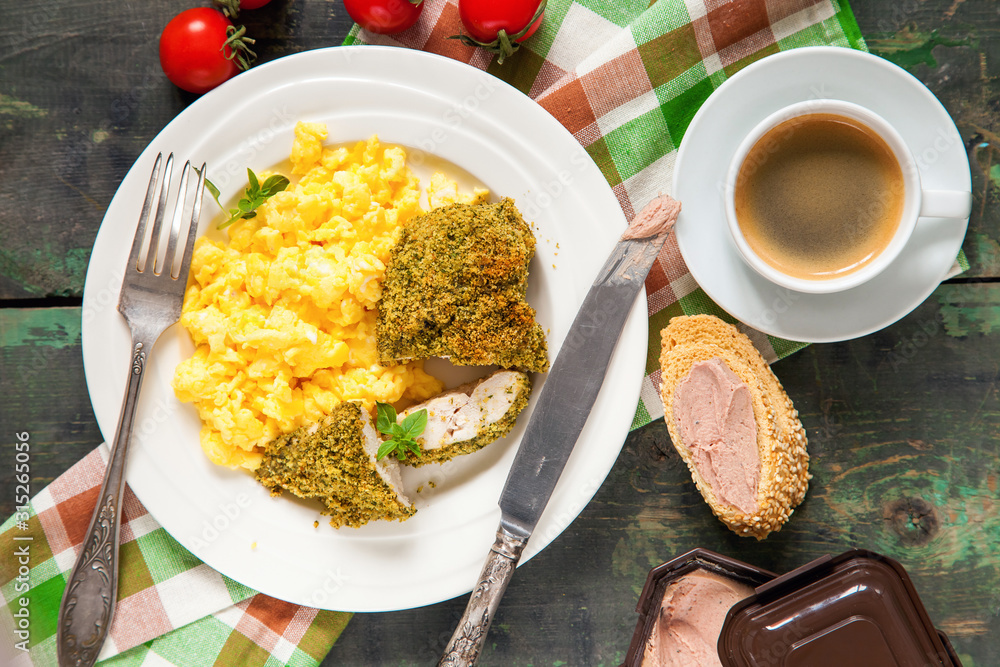 Breakfast - an omelet, chicken fillet in a green breading and coffee on a table. Selective focus. Top view. Copy space. Breakfast - an omelet, chicken fillet in a green breading and coffee on a table. Selective focus. Top view. Copy space.