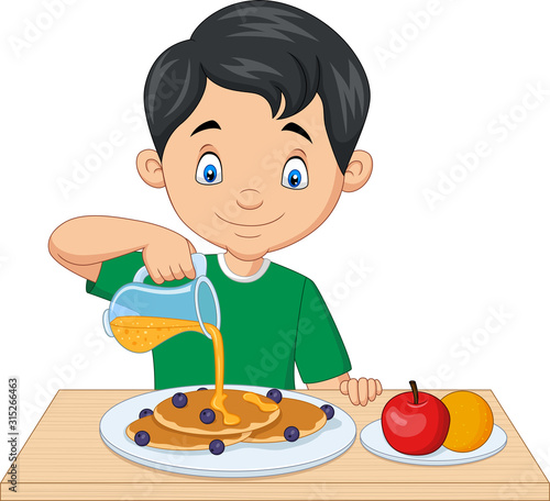 Little boy flowing maple syrup on pancakes with blueberries