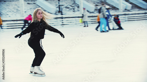 A young woman figure skater skating on the ice rink around people