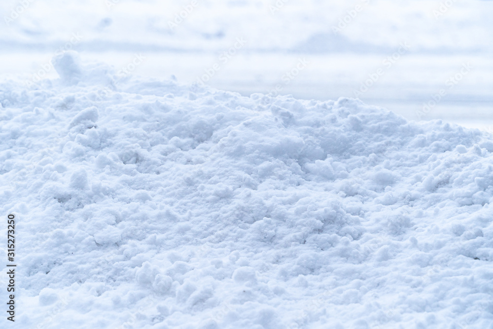 Thick pile of white soft snow covers concrete wall