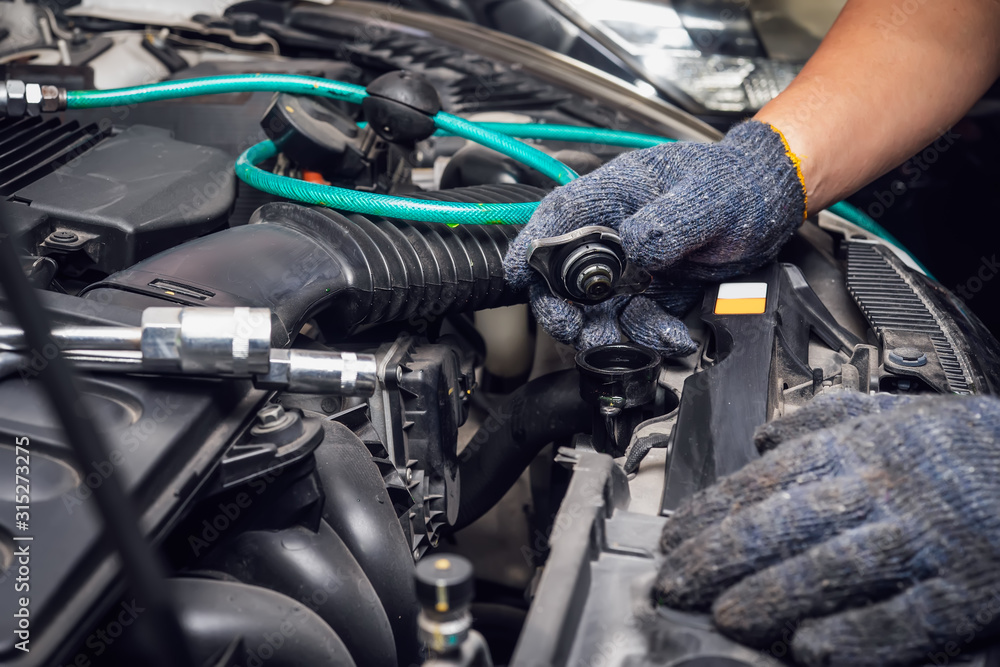 hand of Mechanic check water in car radiator and add water antIfreeze coolant fluid to car radiator at garage , service and maintenance concept . selective focus hand of Mechanic check water in car radiator and add water antIfreeze coolant fluid to car radiator at garage , service and maintenance concept . selective focus