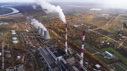 Power plant generating heat and electricity. High pipes and cooling towers are visible. Aerial view.