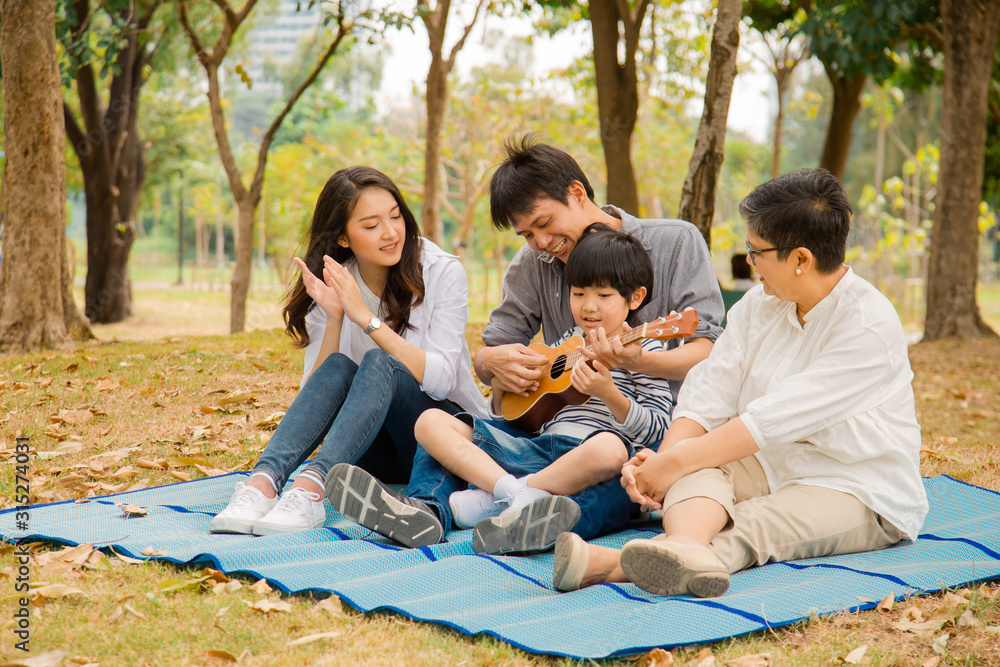 Happy Asian family having fun and enjoying picnic party with playing Ukulele in park,Family Happiness Parents Holiday Vacation Activity Concept Happy Asian family having fun and enjoying picnic party with playing Ukulele in park,Family Happiness Parents Holiday Vacation Activity Concept