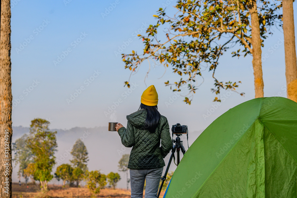woman traveller photographer in motion of enjoy the morning nature of he foggy and mist flowing in front of the forest woman traveller photographer in motion of enjoy the morning nature of he foggy and mist flowing in front of the forest