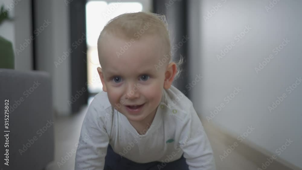 Happy little child boy crawls toward camera on wooden floor. Gimbal motion Happy little child boy crawls toward camera on wooden floor. Gimbal motion