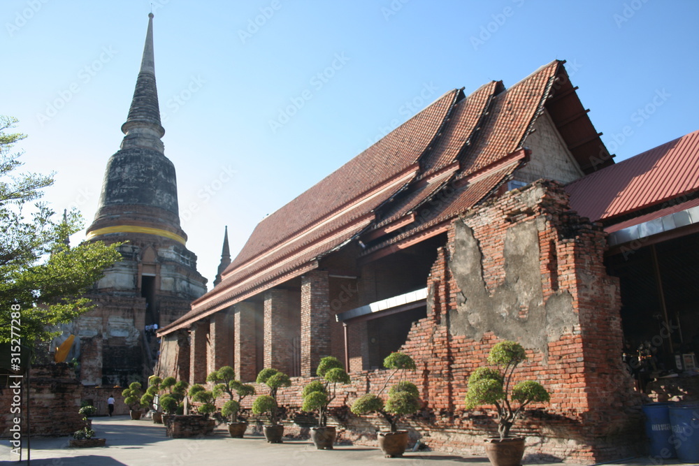 Ancient red brick church with stupa Thai ancient style in Wat Yai Chaimongkol and blue sky, dwarf in pot beside church, Ayutthaya Province, Thailand. 