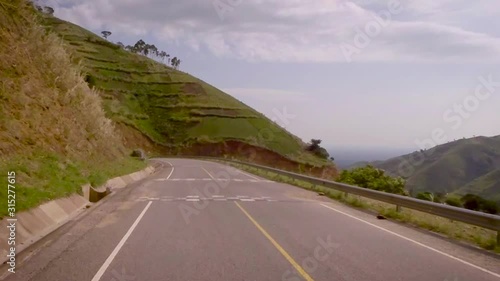 View from a vehicle moving on the road surrounded by beautiful mountains and valley. photo