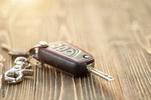 New car keys with black leather cover on wooden table