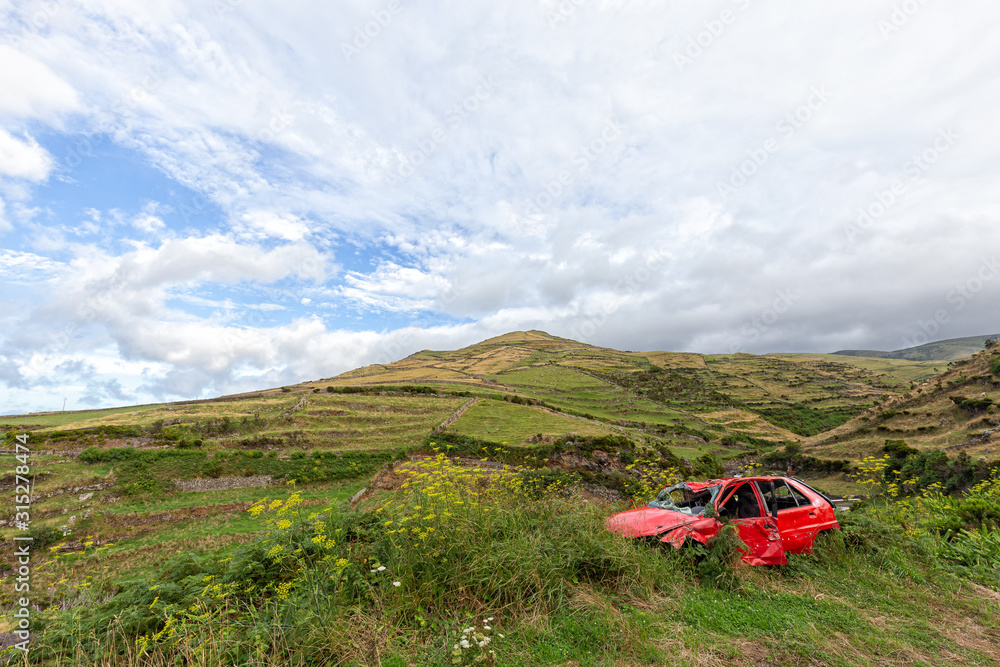 An abandoned red car on the side of the road in rural Flores, Azores.