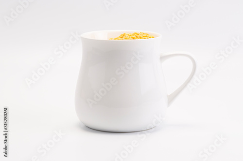 A group of yellow peeled mung bean stay in white mug
