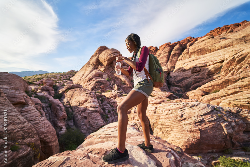 female hiker with water bottle looking at landscape at red rock canyon