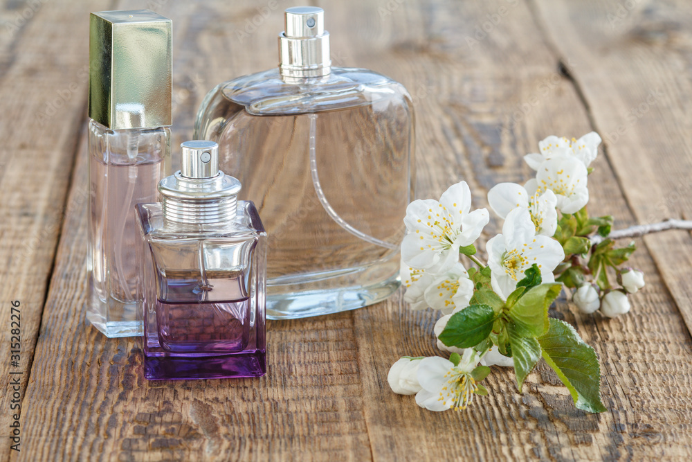 Bottles of perfume with flowers on the wooden background. Bottles of perfume with flowers on the wooden background.