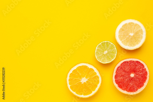 Tropical cutting citrus fruits , orange, grapefruit, lemon and lime on yellow background with copyspace