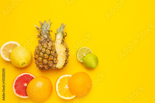 Tropical and citrus cutting fruits   pineapple  orange  grapefruit  lemon and lime on yellow background with copyspace