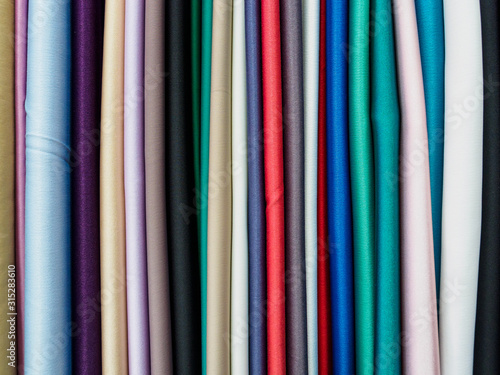 Multi-color knitted fabric samples in vertical position. Woven texture and background
