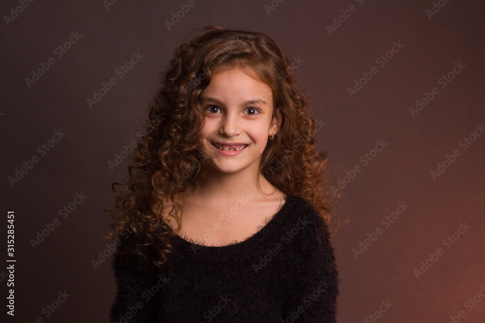 Studio portrait of little girl with long curly hair in a black fluffy jacket and a pink skirt Studio portrait of little girl with long curly hair in a black fluffy jacket and a pink skirt