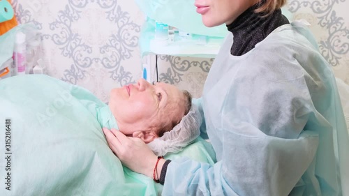 Middle aged woman 50 getting a lifting injection of an injection of hyaluronic acid into the face by a doctor cosmetologist. Cosmetic procedure. photo