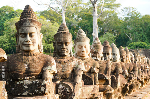 Siem Reap, CAMBODIA - : gates to Angkor Thom and a bridge with statues of asura demons, ruined antiquity, summer sunny day, tuk-tuks on the road photo