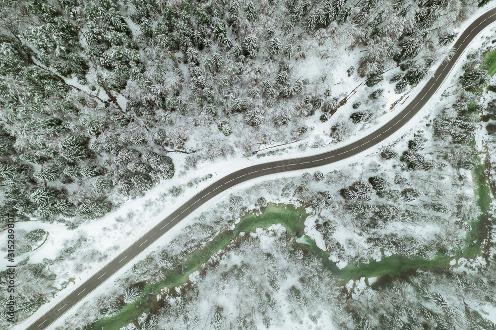 Top aerial view of snow mountain landscape with trees and road. Austria