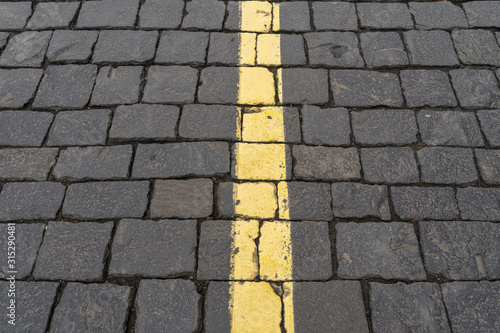 dividing yellow stripe on gray old paving stones