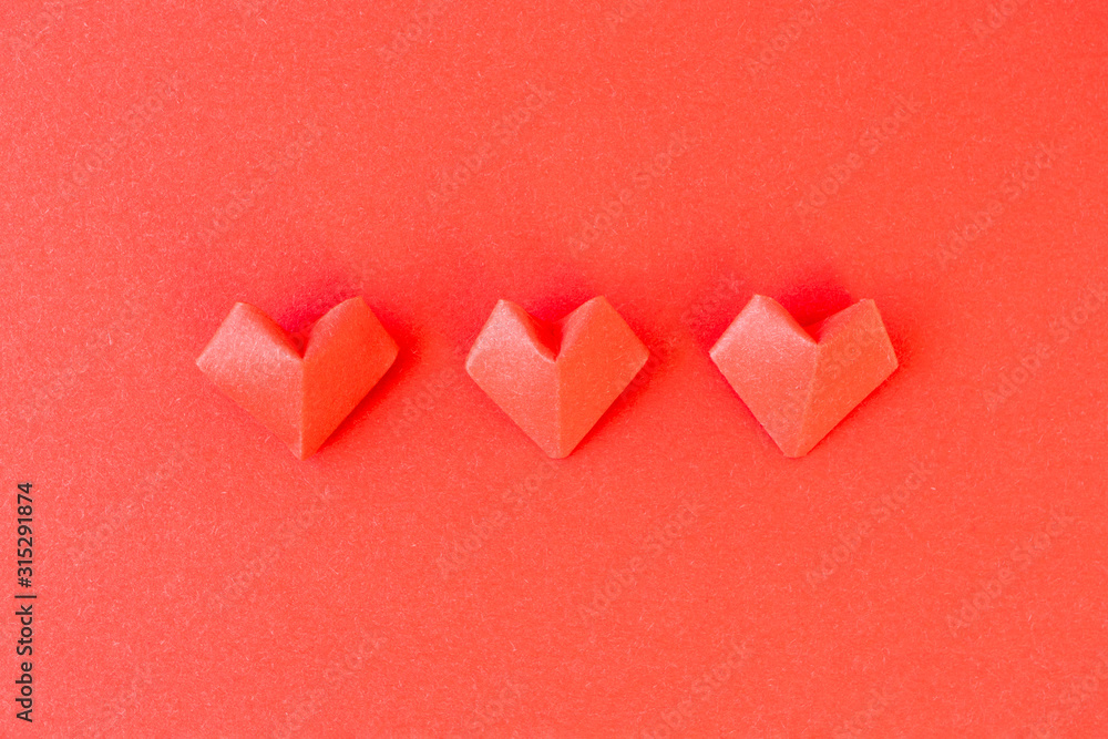 Origami hearts on red paper background, top view. 14th February Valentine's day or wedding invite, postcard. Minimalist composition
