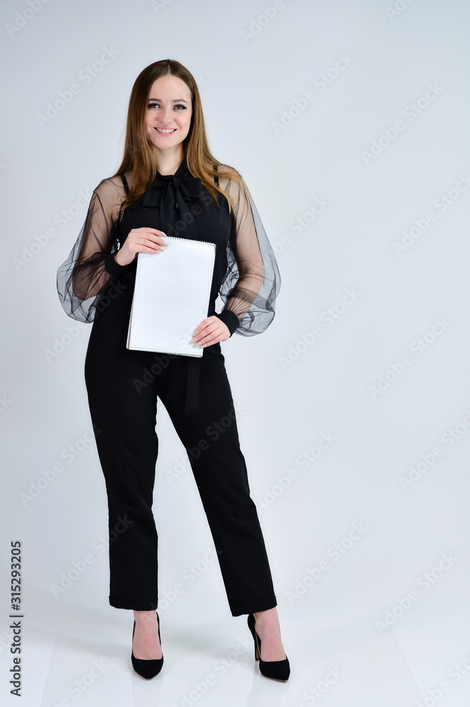 Concept portrait for a banner. Full-length photo of a pretty smiling brunette girl with a folder in her hands with excellent makeup in dark clothes is standing on a white background. Concept portrait for a banner. Full-length photo of a pretty smiling brunette girl with a folder in her hands with excellent makeup in dark clothes is standing on a white background.