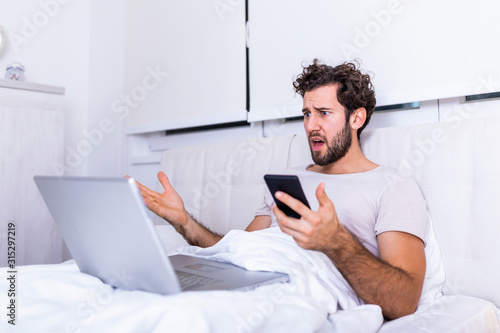 Furious man in bed angry about bad news online or pc software failure, mad helpless man having problem with broken laptop,Working from home in the morrning and drinking coffe photo