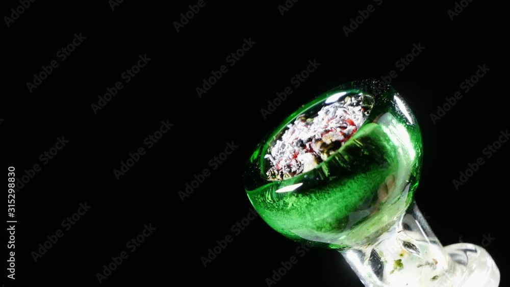 Full cap medical marijuana on fire with a lighter in close-up.Black background. Full cap medical marijuana on fire with a lighter in close-up.Black background.