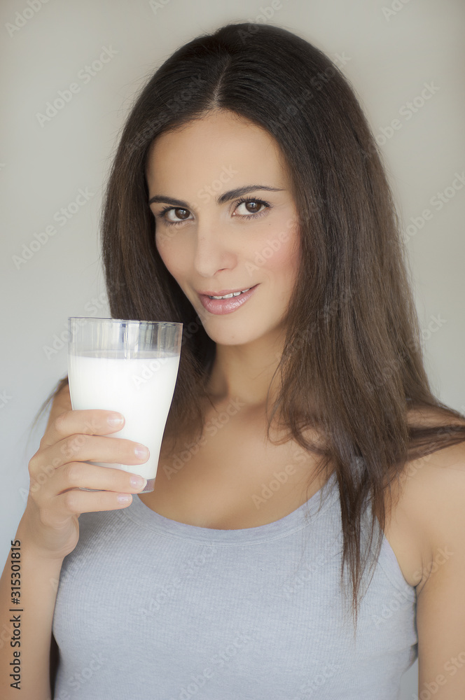 Ragazza con i capelli lunghi tiene un bicchiere di latte Ragazza con i capelli lunghi tiene un bicchiere di latte
