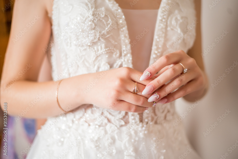 The hands of the bride with gold wedding ring with a diamond. Bride's Preparations. Wedding Morning. Jewelry. Manicure close up. Engagement. The buttonhole with flowers. The hands of the bride with gold wedding ring with a diamond. Bride's Preparations. Wedding Morning. Jewelry. Manicure close up. Engagement. The buttonhole with flowers.