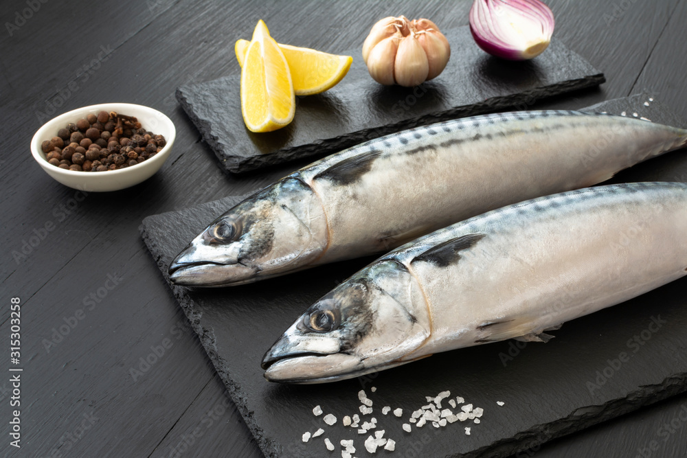 Fresh, raw mackerel with spices on a black concrete background Fresh, raw mackerel with spices on a black concrete background