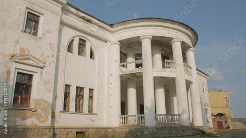 Old abandoned mansion house ruined facade exterior white two-story building Renaissance architecture style with columns at sunset Palace of Earl Xido in Khmelnik Ukraine photo