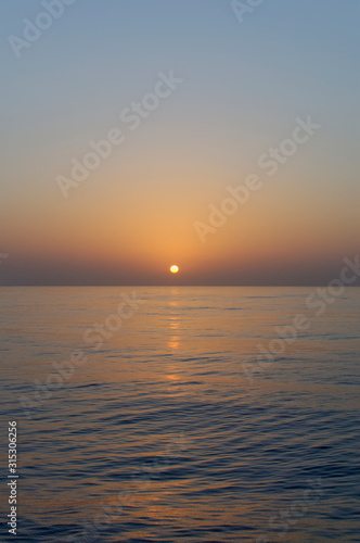 Sunset across calm water as the sun starts to dip over the horizon as a Vessel transits through the Bay of Benin in West Africa, © Julian