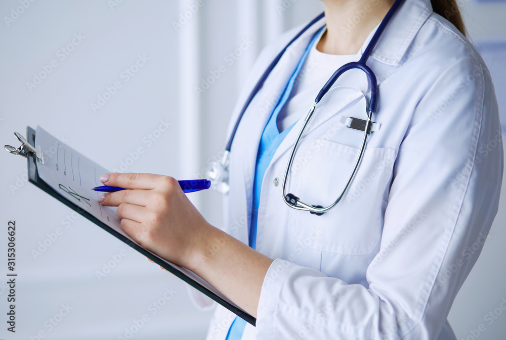 Woman doctor standing with folder at hospital Woman doctor standing with folder at hospital