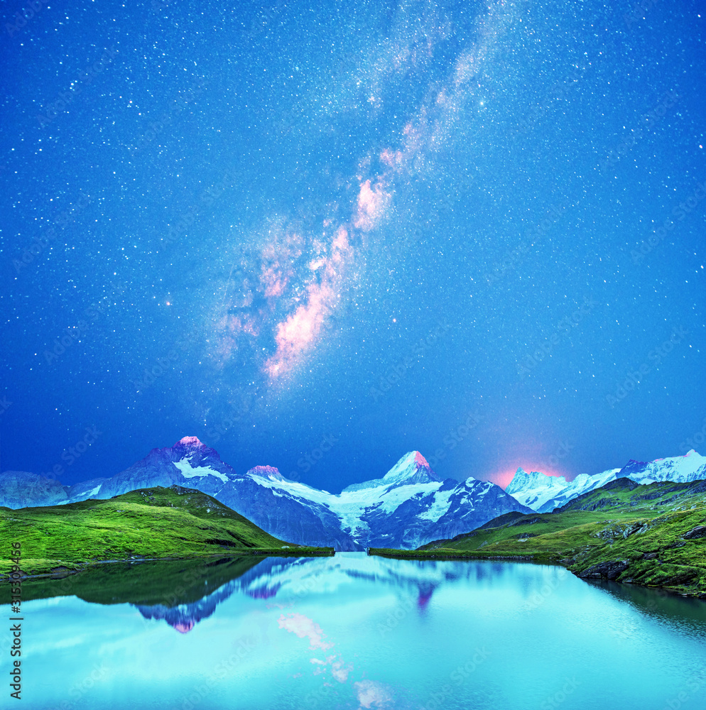 A magical panorama landscape with a lake in the mountains in the Swiss Alps against the background of the stars and the Milky Way. Wetterhorn, Schreckhorn, Finsteraarhorn et Bachsee.